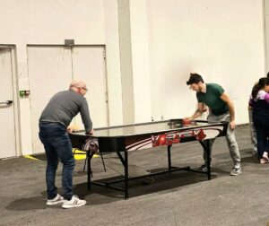 Deux personnes jouent au air hockey en intérieur.