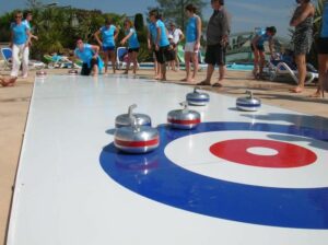Personnes jouant au curling en extérieur près d’une piscine