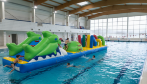Enfants jouant sur un parcours gonflable en piscine.