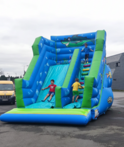 Enfants jouant sur un toboggan gonflable bleu.