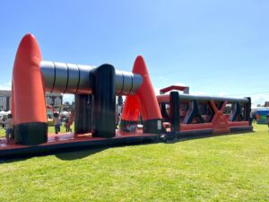 Enfants jouant sur un grand château gonflable rouge.